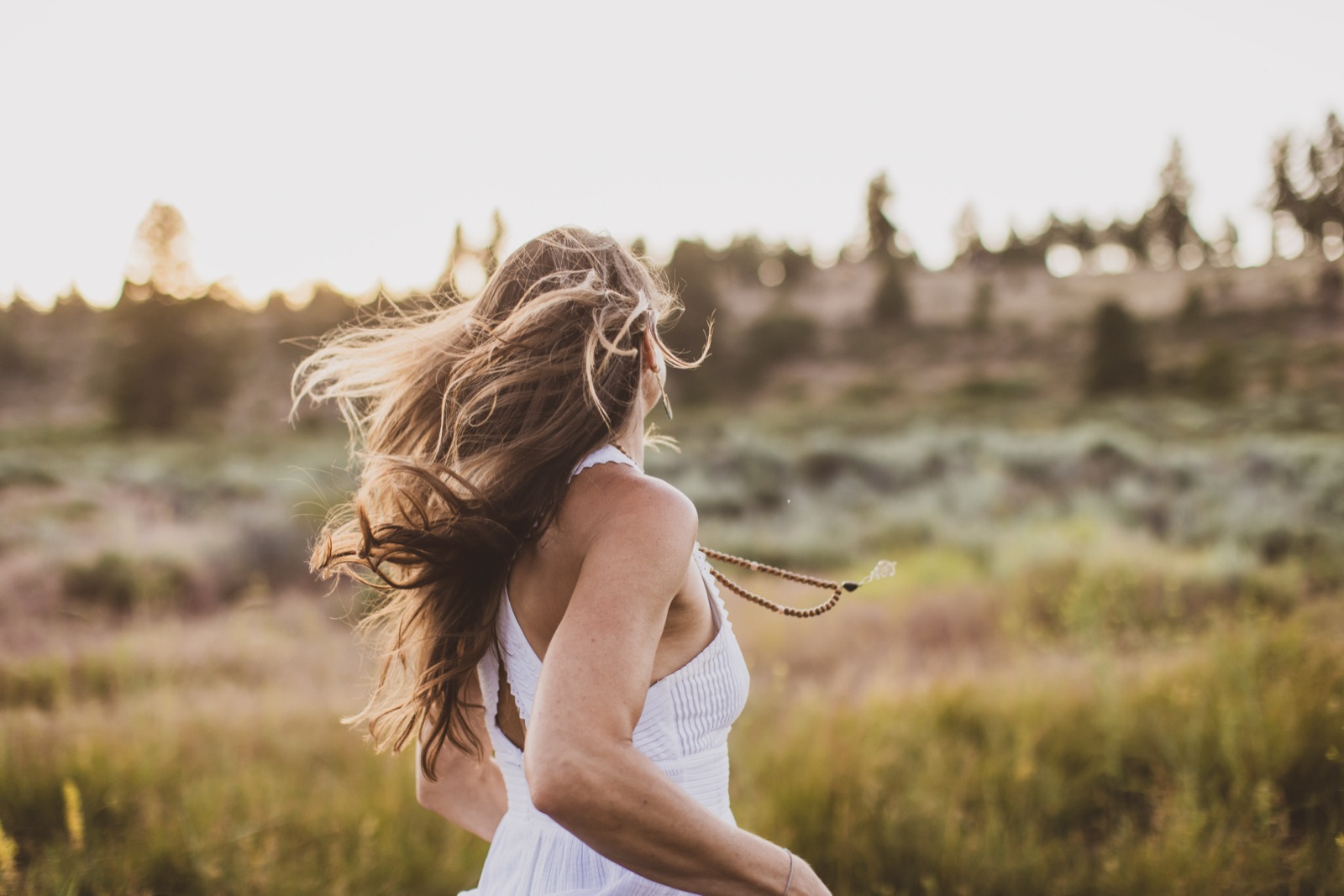 Kaila turning in a white dress in a sunlit field
