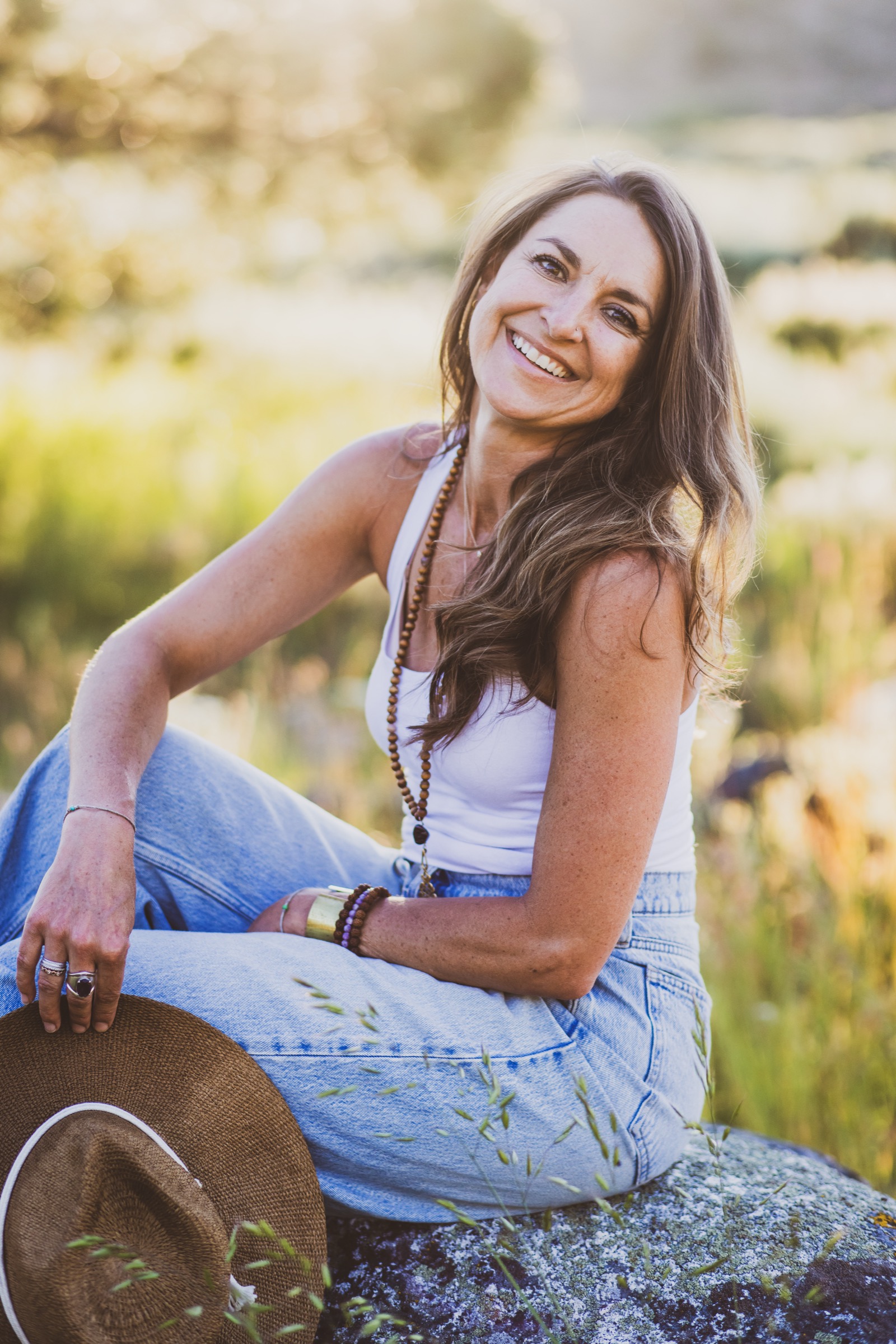 Kaila Leilani sitting in the meadow grass at golden hour, laughing